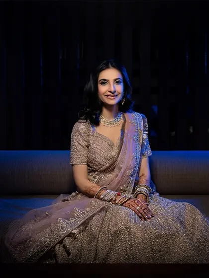A wide shot of the bride, looking elegant and poised. The dark, moody lighting makes her and her lehenga stand out.