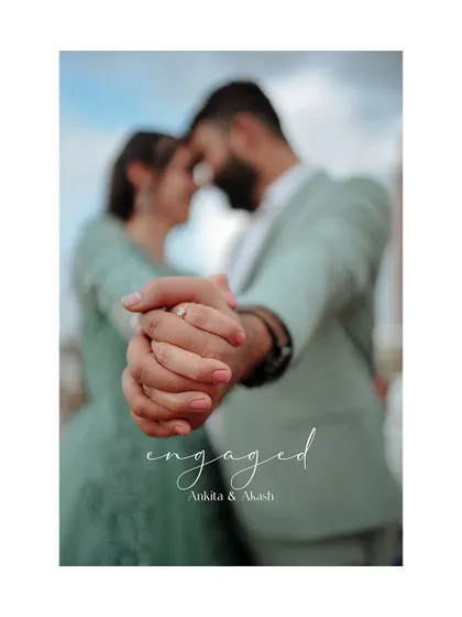 A beautiful engagement announcement photo focusing on the couple's hands and the ring. The soft focus on the couple in the background adds a touch of romance and artistry.