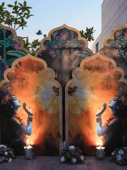A stunning and artistic backdrop for a Krishna party, featuring beautiful paintings and lit by candles for a serene evening event.
