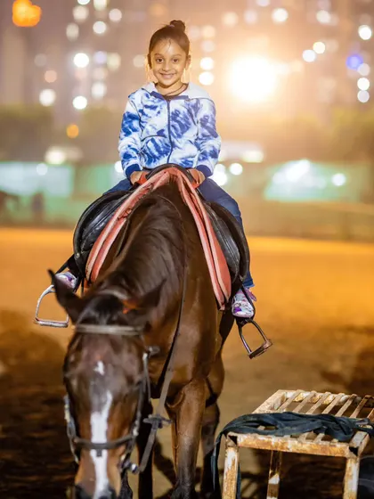 A young girl smiles brightly during her evening joy ride. The lights of the arena create a magical experience for our youngest visitors.