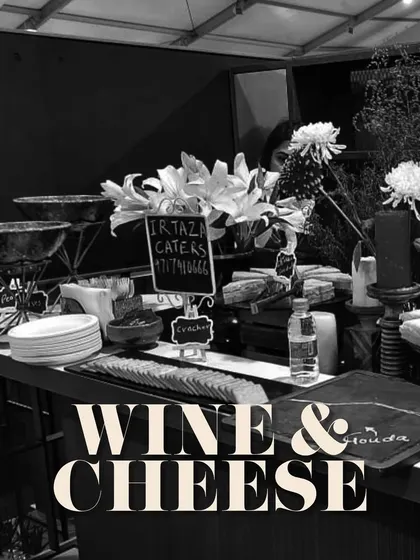 A chic and moody shot of a wine and cheese station, perfect for a corporate networking event. The black and white photo emphasizes the elegant lines and sophisticated atmosphere.