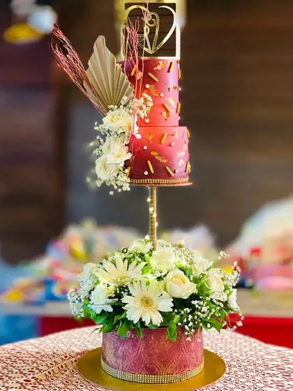 A unique floating tier cake design for a wedding. The top two tiers are suspended on a stand above a base of fresh flowers, creating a dramatic and beautiful effect.