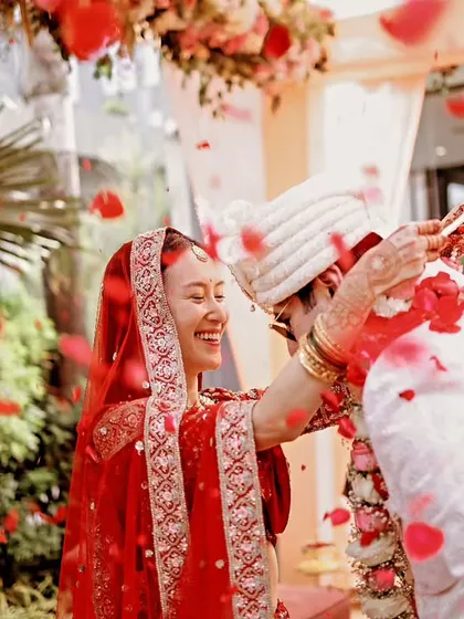 A happy, candid moment during the Varmaala exchange, with the couple showered in red rose petals.