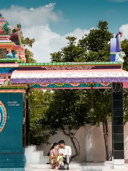 A wider view of the couple at the temple, showcasing the vibrant architecture and serene setting.