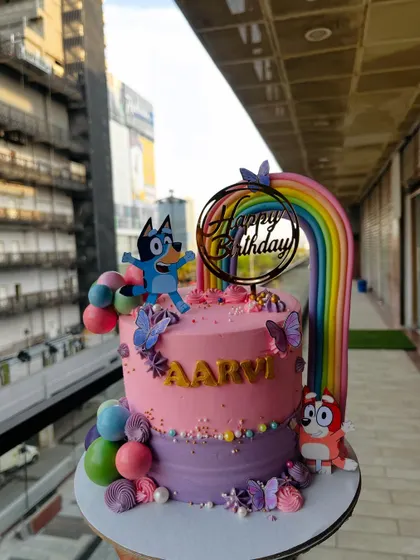 A colorful and fun cake featuring characters from the popular kids' show Bluey. The design includes a rainbow, character toppers, and vibrant sprinkles for a cheerful birthday party.