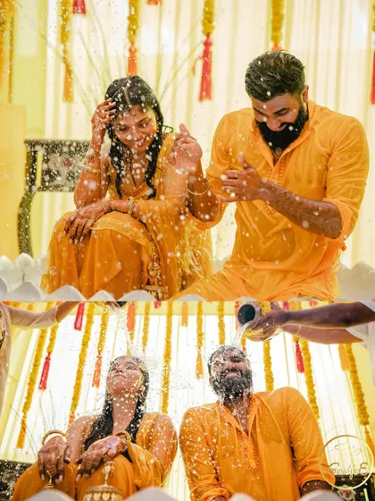 The couple enjoying the Haldi rituals together, getting showered with water and blessings.