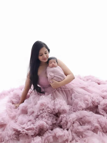 A beautiful composition showing the mother seated in a sea of pink tulle, holding her swaddled newborn. It's a portrait that feels like it's straight out of a fairytale.