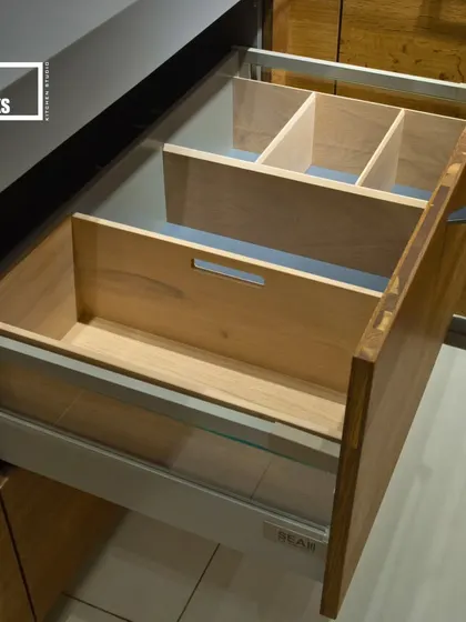 Organization is key, especially in the kitchen. This drawer features custom wooden dividers and organizers, keeping cutlery and utensils neatly in place. The glass sides add a touch of modern elegance.