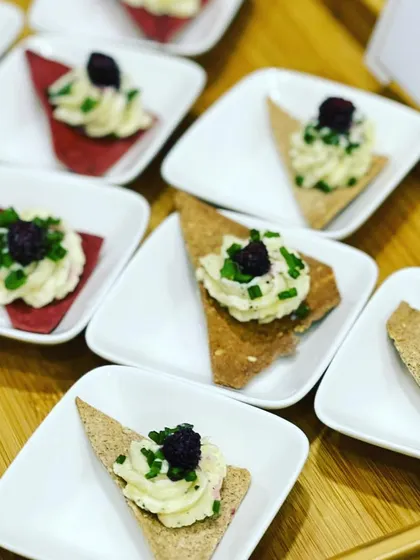 Sour cream and chive dip served on crispy multigrain crackers, garnished with fresh blackberry for a touch of sweetness.