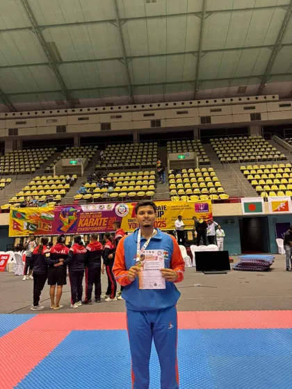 Jitendra Kumar holding his gold medal and certificate on the competition mat at the 9th South Asian Karate Championship. A clear view of the arena where champions are made.