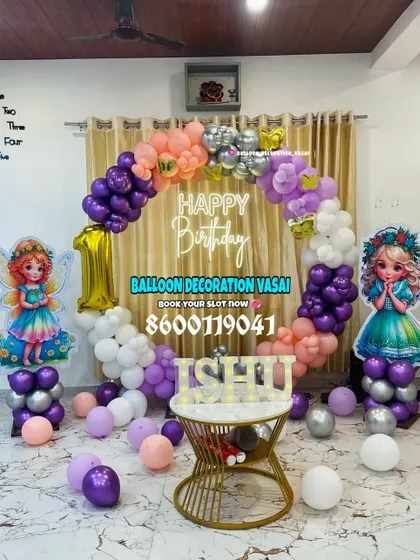 A whimsical fairy theme for Ishu's first birthday. This ring backdrop is decorated with purple, peach, and white balloons, with two fairy cutouts and a custom name table.