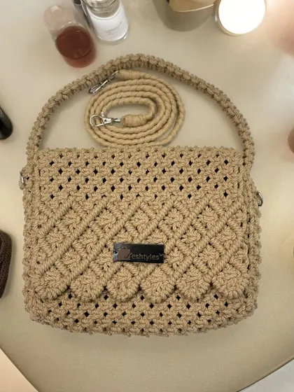 This beige sling bag with a scalloped flap is perfect for any occasion, from brunch to a wedding.