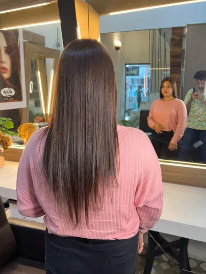 A client admiring her fresh haircut and color in the mirror. The style is straight with a slight inward curve.