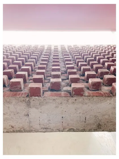 A detail of protruding bricks, creating a textured pattern on a wall. This shows the careful, deliberate use of a simple material.