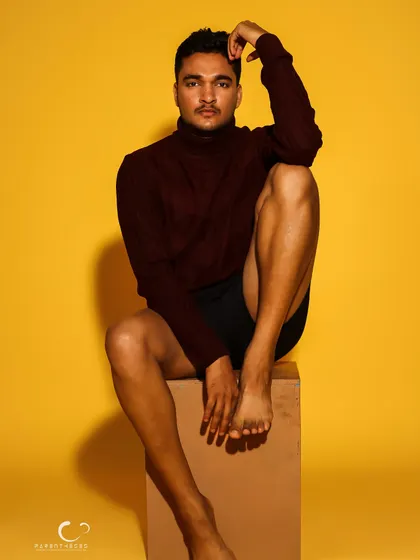 A minimalist portrait focusing on form and physique. The simple styling and confident pose against the yellow background create a powerful, artistic statement.