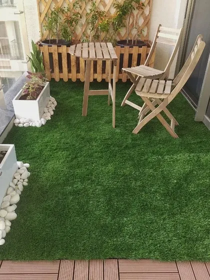 An identical image showing the functional and attractive combination of artificial turf and WPC tiles, creating distinct zones for planting and seating on a compact balcony.