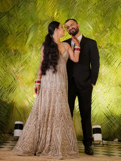 A sweet and playful moment where the bride lovingly teases the groom, captured against a lush, tropical-themed photo wall.