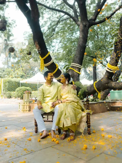 A serene portrait of the couple under a beautifully decorated tree during their Haldi ceremony. This quiet moment provides a lovely contrast to the usual playful chaos.