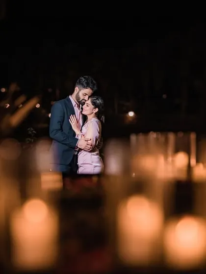 An artistic shot of the couple embracing, viewed through a field of glowing candles that we arranged to create a dreamy, romantic atmosphere.