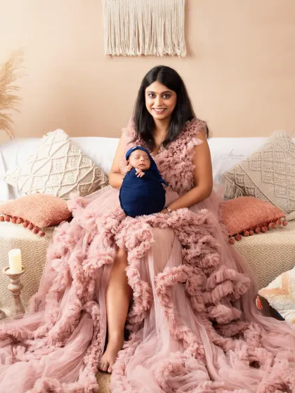 A proud new mother holds her tiny newborn. We offer a selection of beautiful gowns for moms to wear during the shoot.
