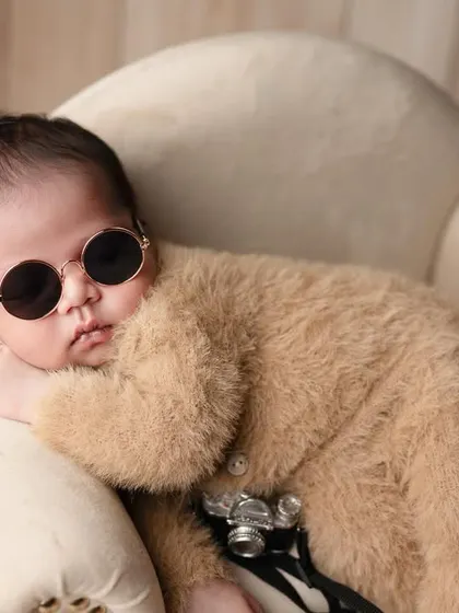 This little boy has all the swag. Dressed in a fuzzy bear-suit and cool sunglasses, he's the epitome of newborn coolness.