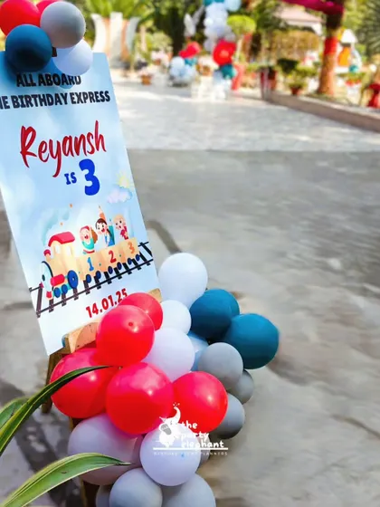 A personalized welcome sign for Reyansh's 3rd birthday party, designed to look like a train ticket for the 'Birthday Express', surrounded by a colorful balloon arrangement.