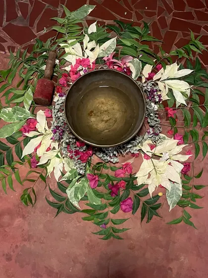 A beautiful arrangement of flowers and leaves cradling a singing bowl before a session. This ritual honors the sacred elements of nature and sets an intention of healing and peace for the practice.