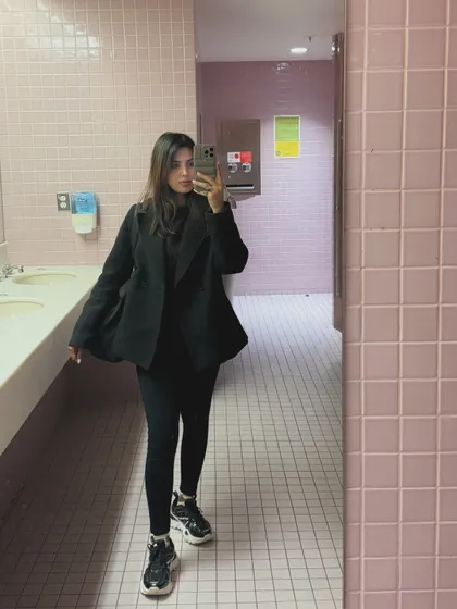 A full-length mirror selfie of an all-black college outfit with chunky sneakers.