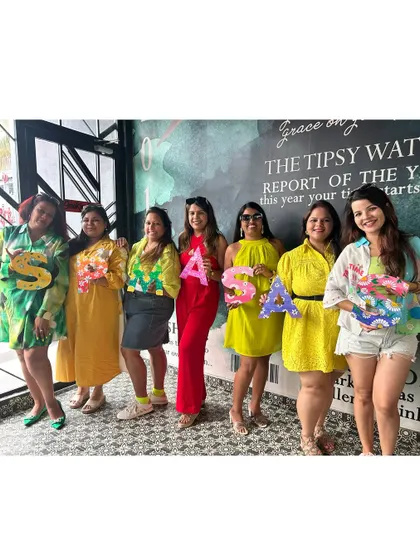 This group of friends is proudly showing off the personalized letters they painted at their kitty party. It's a fun way to create something unique and meaningful.