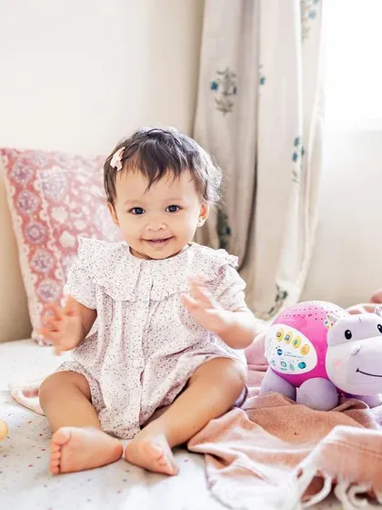 This little one is having a great time with her favorite pink hippo toy. At-home sessions allow babies to be surrounded by their familiar comforts.