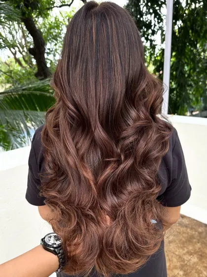 Luxurious, flowing waves on long, dark hair with subtle chocolate highlights. This style is all about volume and movement.