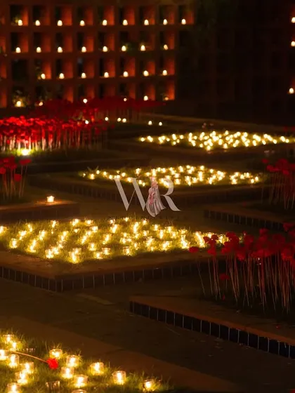 Another angle of the candle and poppy garden, showing the geometric layout of the installation. The contrast between the glowing lights and the dark night creates a powerful visual impact.