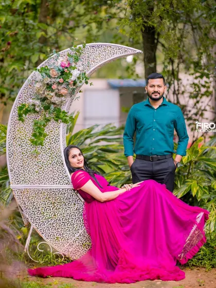 A stylish couple posing with the floral moon prop. The woman's bright pink gown adds a fun and vibrant feel to this whimsical pre-wedding portrait.