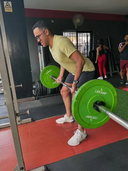 A client performs a bent-over barbell row, a key exercise for building a thick, strong back.