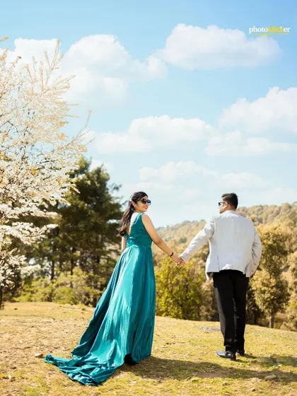 A couple walks away hand-in-hand through a beautiful meadow with blooming white trees, capturing a sense of journey and togetherness.