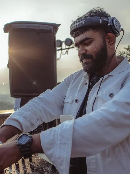 A candid photo of me mixing at a sundowner party, with the sun setting in the background. These are the golden hour gigs I love.