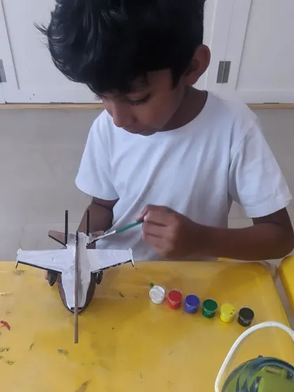 Painting the base coat on a wooden jet model. This is the first step where kids begin to visualize their final design.