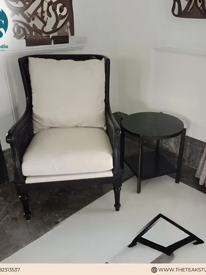 A comfortable lounge chair with a dark wood frame and deep, plush white cushions. This chair is perfect for creating a relaxed yet elegant seating area, ideal for long conversations or quiet afternoons.
