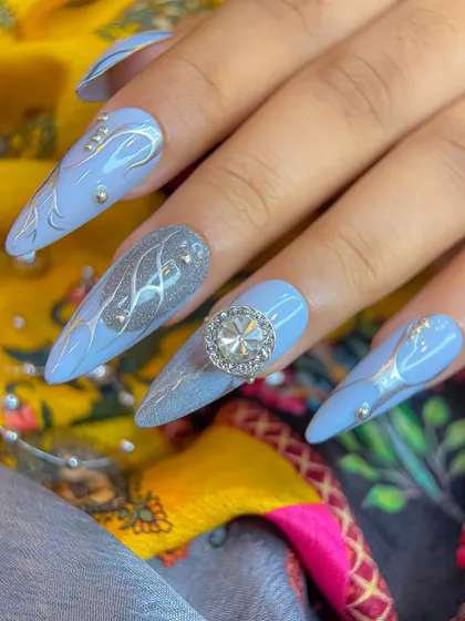 A full view of the hand, showcasing the complete set of grey and silver Navratri nails against a vibrant, traditional fabric.