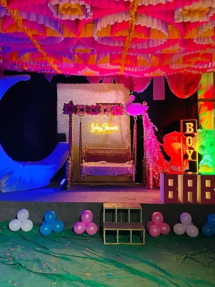 Another view of the baby shower stage under blue lighting, highlighting the moon prop and neon sign.