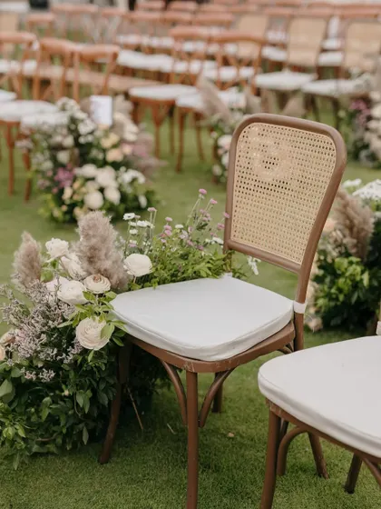 Guest seating for the vow exchange, with floral arrangements lining the aisle.
