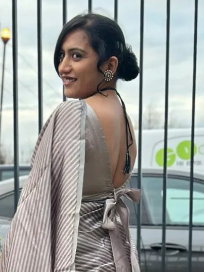 A stunning silver satin saree paired with a custom blouse featuring a deep, open back with a simple tie.
