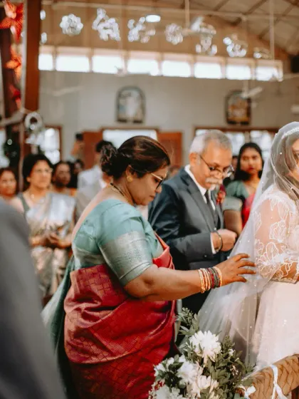 A mother's reassuring touch as the bride looks towards her groom at the altar. A small, quiet gesture full of love and support.