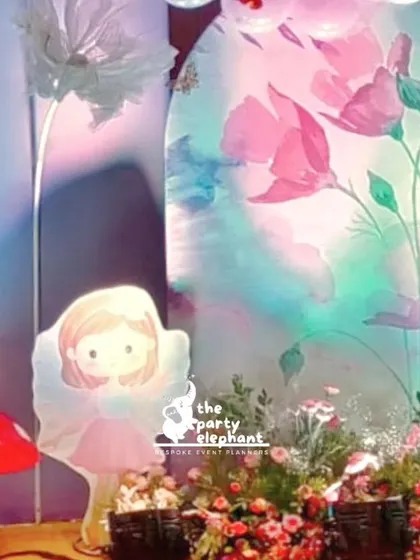 A detailed shot of the fairy and mushroom cutouts against the beautifully lit floral backdrop. We use layered props to create a three-dimensional, storybook feel.