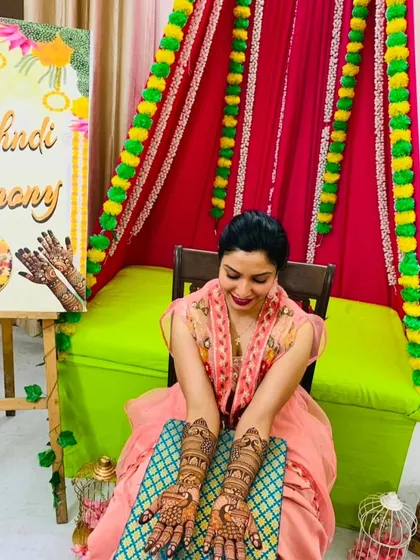 Another angle of our happy bride at her home mehndi ceremony. The detailed peacock designs on her arms are a classic choice for wedding henna.