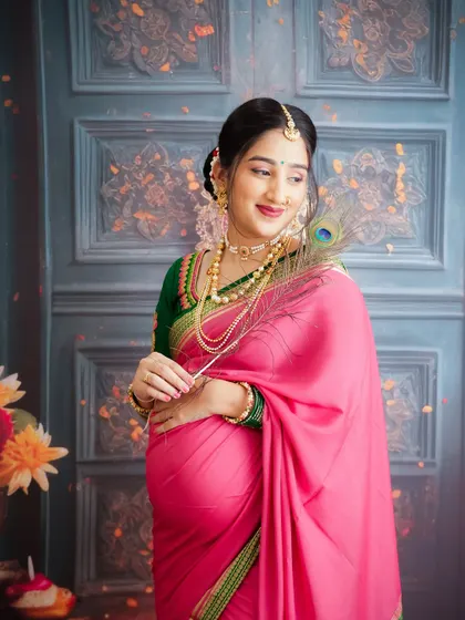 A beautiful traditional portrait of a mom-to-be in a pink and green saree, holding a peacock feather. A celebration of culture and new life.