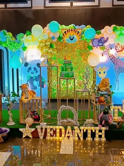 A vibrant jungle theme with a green sequin backdrop and lots of animal friends. The light-up name and "BABY" blocks are perfect for a first birthday.