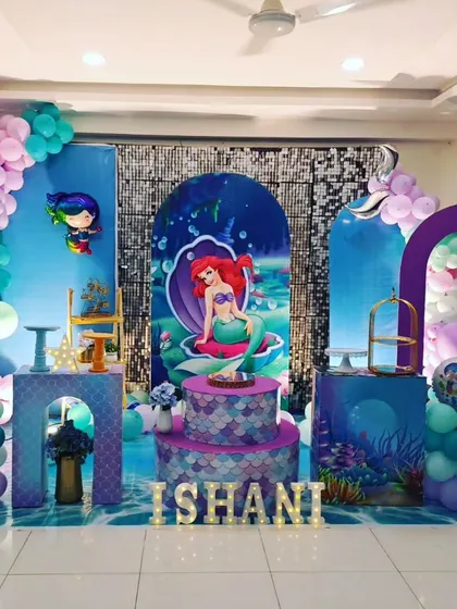 A grand mermaid theme for Ishani's 5th birthday. This full-stage setup includes multiple backdrops, a shimmering floor decal, and an elaborate balloon arrangement to create a magical underwater kingdom.