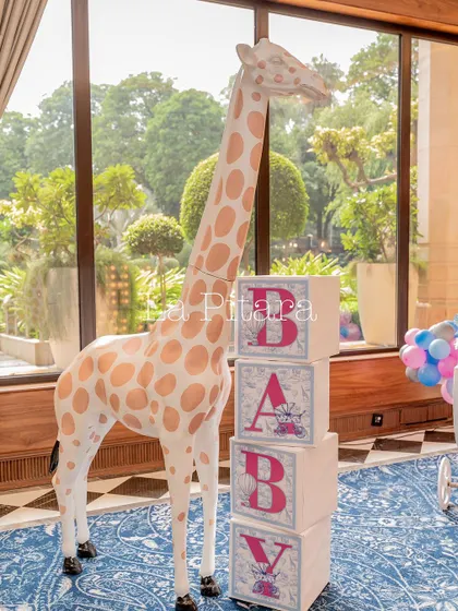 A life-sized giraffe prop next to themed 'BABY' blocks, adding a touch of whimsy to the elegant baby shower.