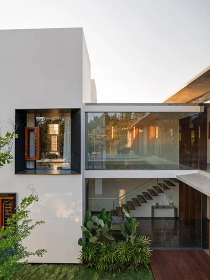 The Long House is designed as a series of interconnected blocks and voids, with a glass-walled bridge connecting two volumes over an open courtyard.